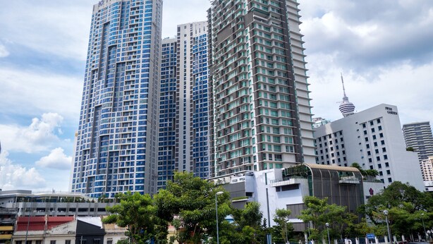 A modern high-rise building with a unique rooftop structure, surrounded by other high-rise buildings and greenery.