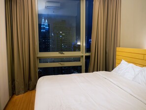 A hotel room with a large window, a bed with white bedding, and a wooden headboard. - Wallace P Staycation (Kuala Lumpur)