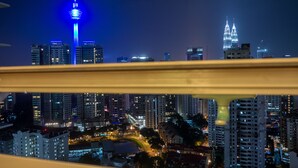 A nighttime cityscape with illuminated skyscrapers, including a prominent tower with blue lights.
