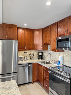 A modern kitchen with wooden cabinets, stainless steel appliances, and a brick backsplash.