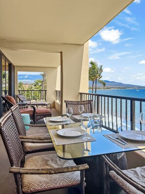 Comedor con mesa lista para dos, con vista a la playa y al océano.