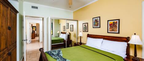 A hotel room with a bed, a nightstand, a ceiling fan, a wardrobe, and a mirror.
