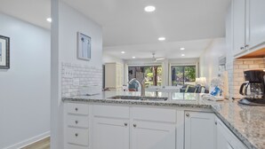 Une cuisine moderne avec des meubles blancs, des plans de travail en granit et un îlot central.