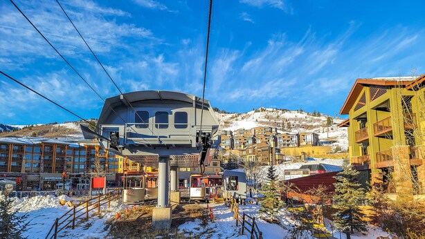 A cable car station with a cable car, buildings, and snow-covered hills in the background. - Park West Town Home 3920: 5 Bedroom 3.5 Bath (Park City)
