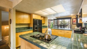 A kitchen with wooden cabinets, a black refrigerator, a stove, and a green tiled countertop. - Park West Town Home 3920: 5 Bedroom 3.5 Bath (Park City)