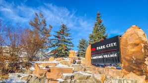 A sign for Park City Canyons Village with a clear blue sky and snow-covered ground. - Park West Town Home 3920: 5 Bedroom 3.5 Bath (Park City)