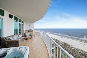 Ein Balkon mit Blick auf den Strand, einer Whirlwanne und Sitzgelegenheiten im Freien.