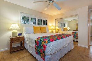 A bedroom with a bed, bedside lamps, a nightstand, a ceiling fan, and a large mirror.