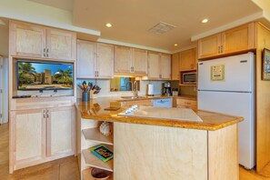 Eine Küche mit Holzausbau, einer Granitabdeckung, einem eingebauten Backofen und einem Kühlschrank.