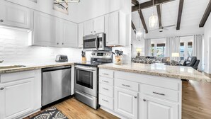 A modern kitchen with white cabinetry, stainless steel appliances, and a large island.