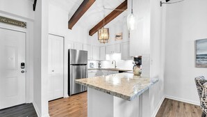 A modern kitchen with white cabinetry, a granite countertop, and a stainless steel refrigerator.