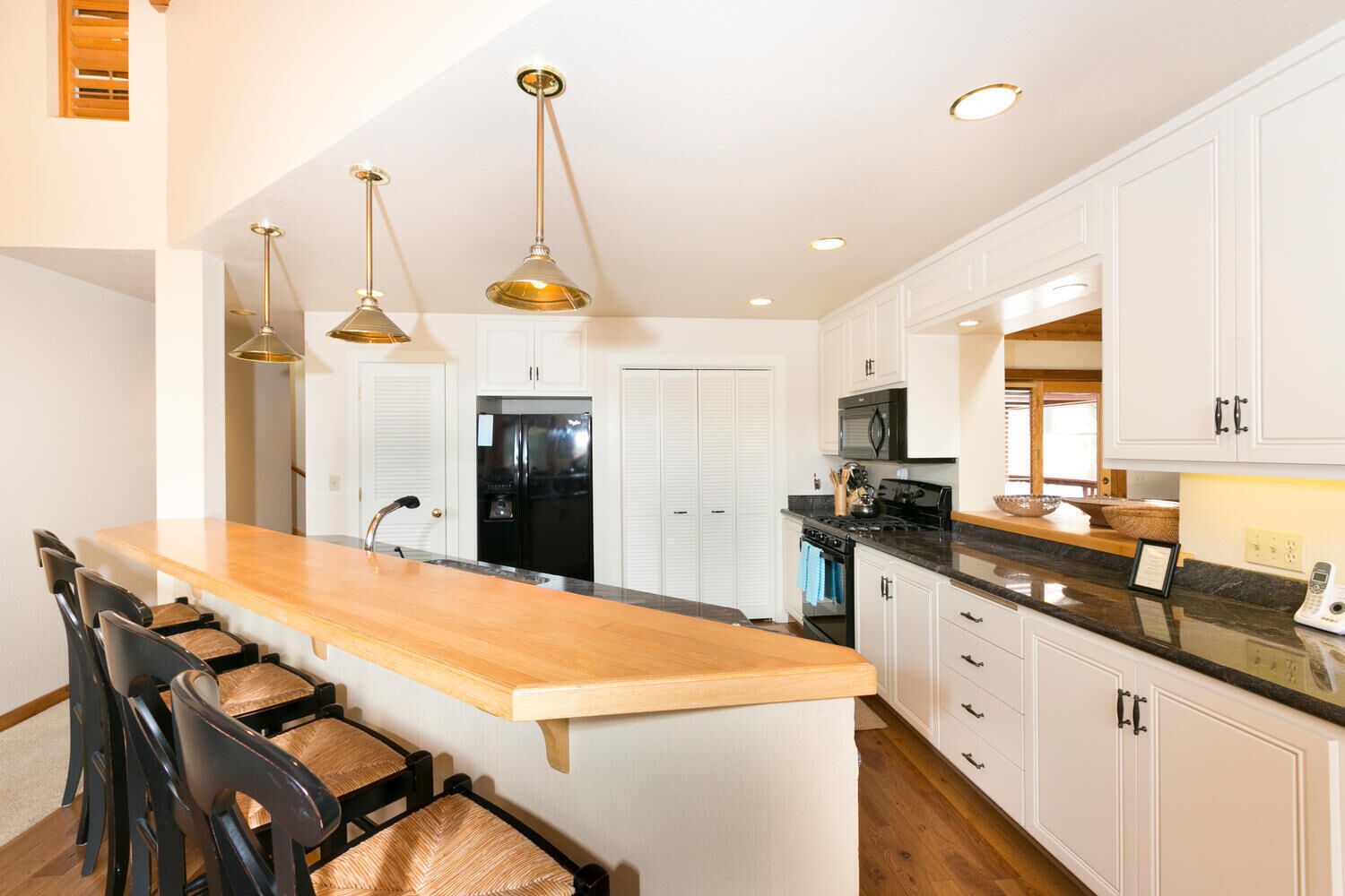 Una cocina moderna con armarios blancos, una isla de madera e iluminación colgante.