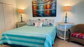 Un dormitorio con cama, una silla, una mesa redonda y un cuadro en la pared.