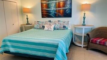 Une chambre à coucher avec un lit, une chaise, une table ronde et un tableau accroché au mur.
