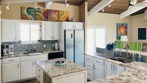 Una cocina moderna con gabinetes blancos, encimeras de granito y electrodomésticos de acero inoxidable.