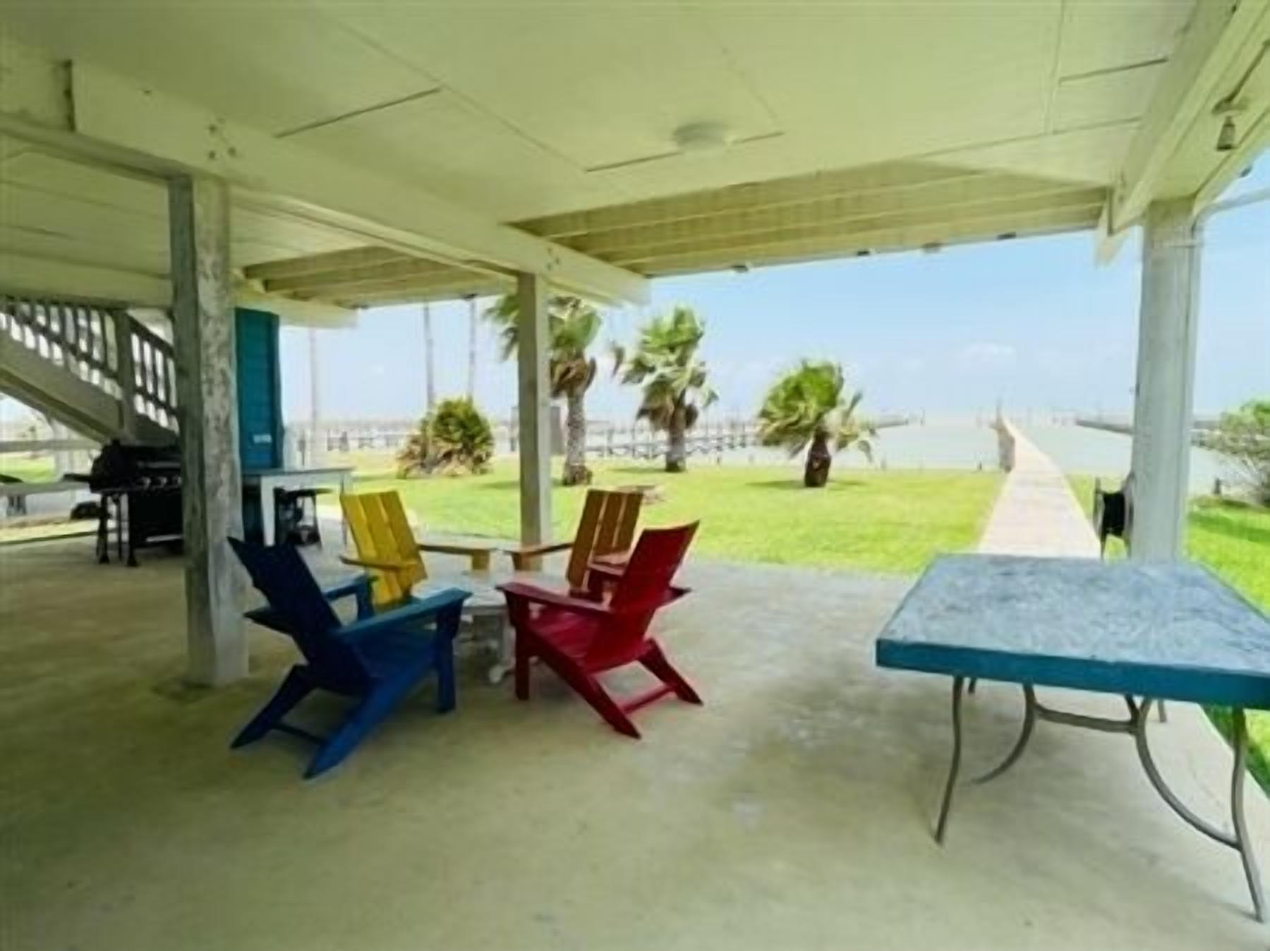 Un espacio de estar al aire libre cubierto con vista a la playa y palmeras.