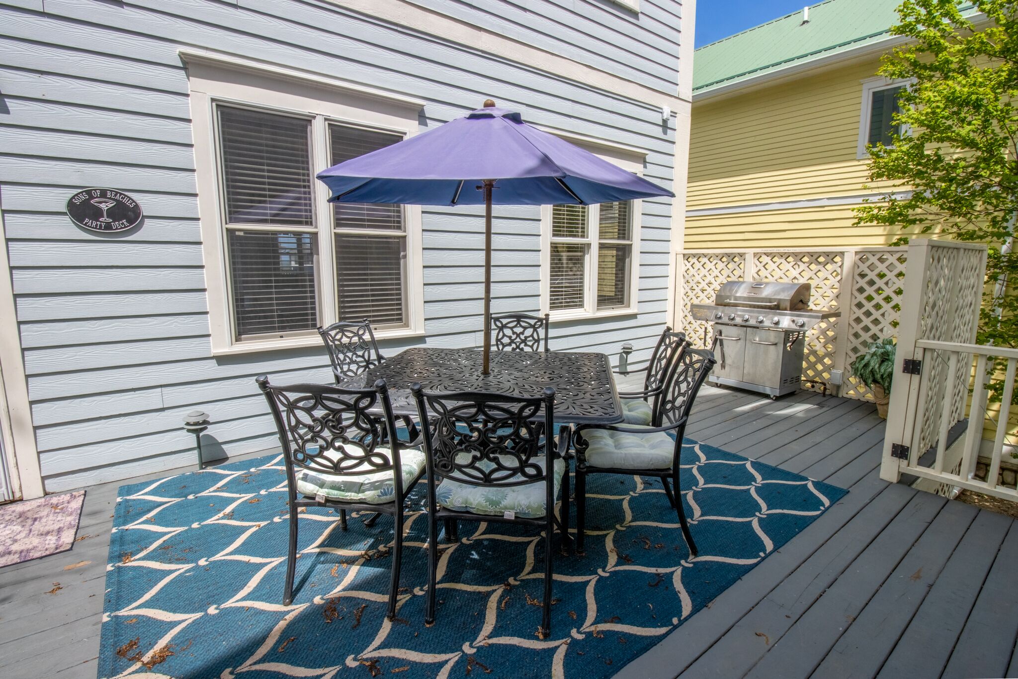A patio with a table and chairs, a grill, and a sign that reads "King of Beaches Party Place".