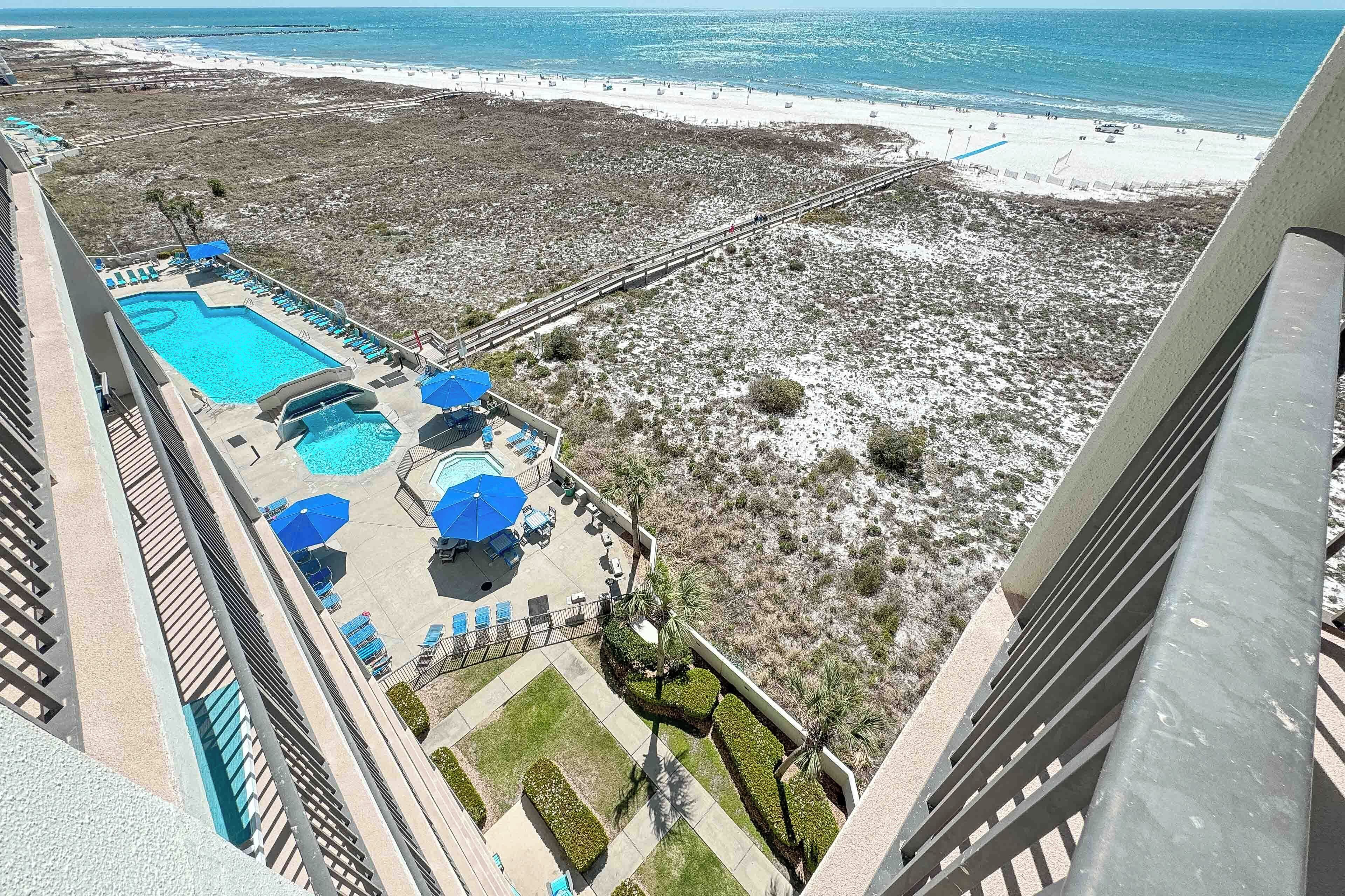 A hotel with a pool, sun loungers, and a view of the beach.
