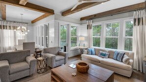 A spacious living room with a large sofa, two armchairs, a coffee table, and a dining area.