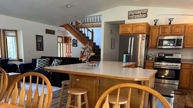 A modern kitchen with wooden cabinets, stainless steel appliances, and a central island with stools.