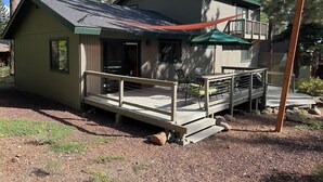 A cabin with a deck, a covered patio, and a small outdoor seating area.