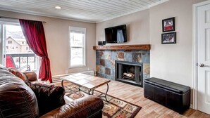 Una sala de estar acogedora con chimenea, sofá de cuero y televisor montado en la pared.