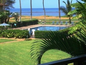 A pool area with lounge chairs and a view of the ocean.