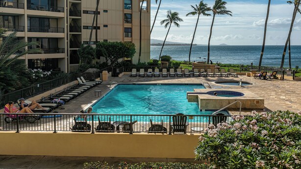 A hotel pool area with multiple lounge chairs, a hot tub, and a view of the ocean. - Oceanfront Oasis: Ground Floor Retreat - Sugar Beach #130 (Kihei, Maui)