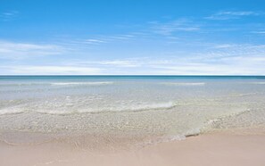 Ein Strand mit klarem, flachen Wasser und einem sandigen Ufer.
