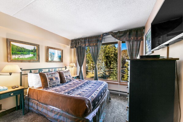A hotel room with a large bed, a TV, and a window with curtains. - Walking Distance to Keystone Conference Center, Mountain Views (Keystone)