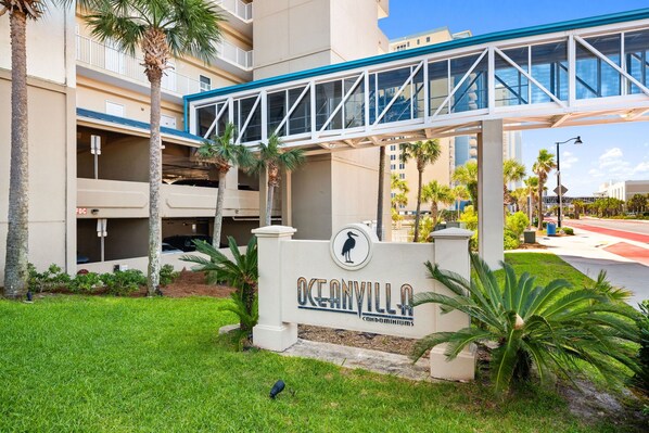 A gated entrance with a sign for Oceanville Condominiums, a covered walkway, and a parking garage. - Ultimate Beachfront Getaway: Gulf front condo on the 12th floor! (Panama City Beach)