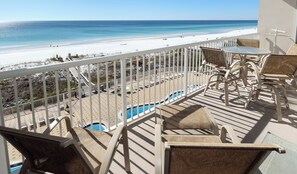 A balcony with a view of a beach and a pool.