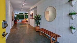 Un couloir moderne agrémenté d’un banc, d’un miroir rond et de plantes en pot fixées au mur.