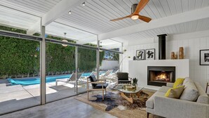 Un salon moderne doté d’une cheminée, d’une piscine et d’une porte vitrée donnant sur un espace extérieur.