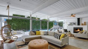 Un salon moderne avec un canapé d’angle, un pouf et une cheminée.