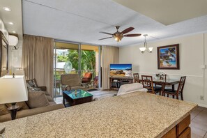 A spacious living area with a large kitchen island, a dining table, and a ceiling fan.