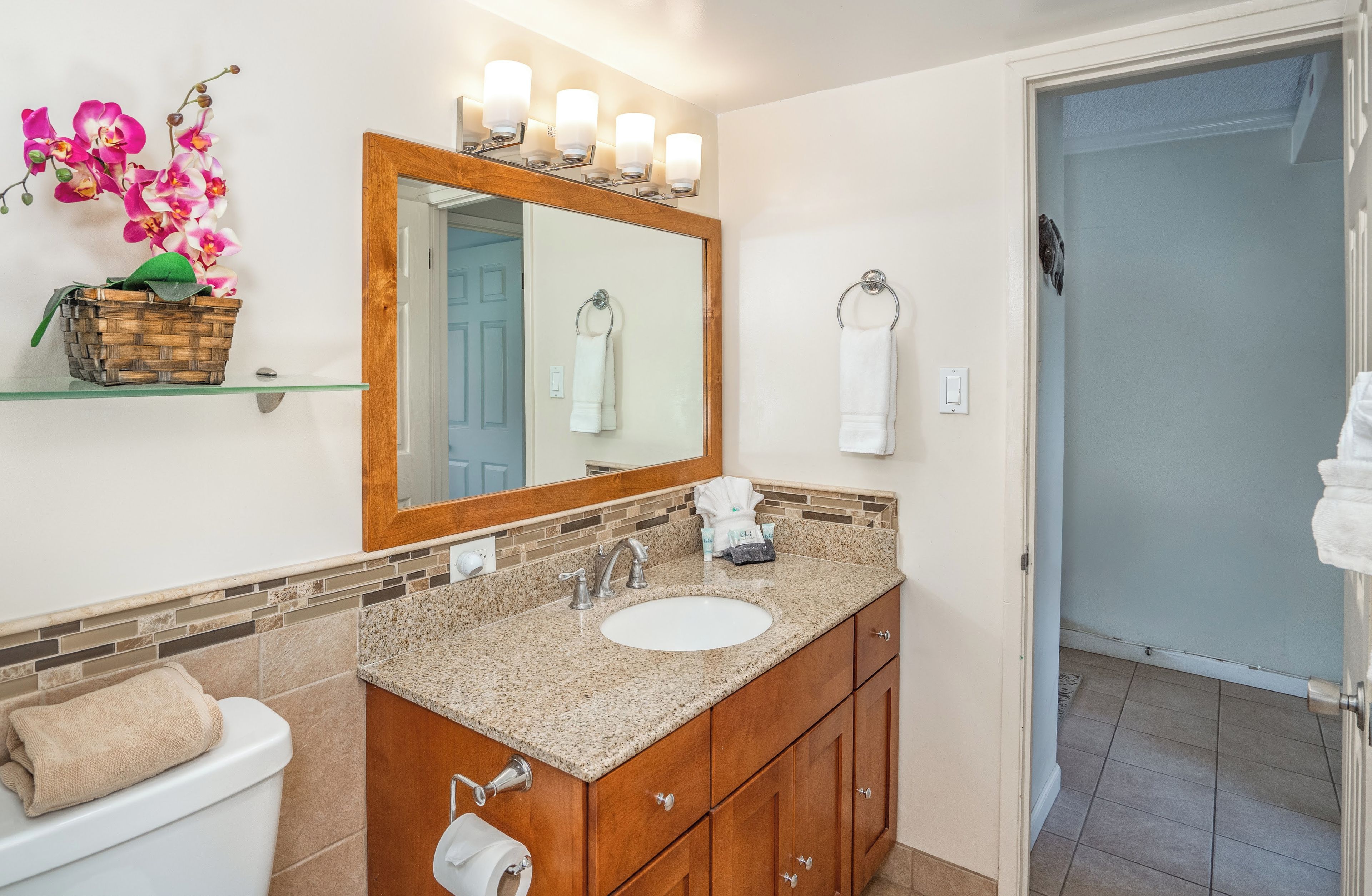 A bathroom with a vanity, sink, mirror, and a towel rack.