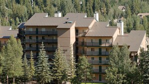 A multi-story residential building with balconies, surrounded by trees. - Lionshead Village Condo With Mountain Views, Hot Tubs, Short Walk to Gondola (Vail)