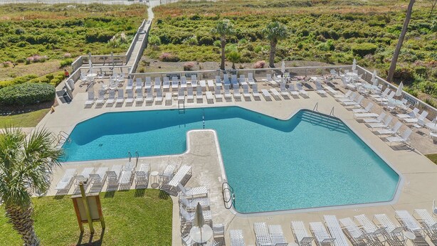 Zona de piscina con sillones y vista al océano.