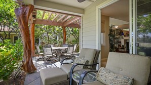 A covered patio area with outdoor furniture, including a sofa and chairs, and a dining table. - Summer Special! Discover luxury at Leilani Kai, a 3BR condo in beautiful Waikoloa, HI. (Waikoloa Village)