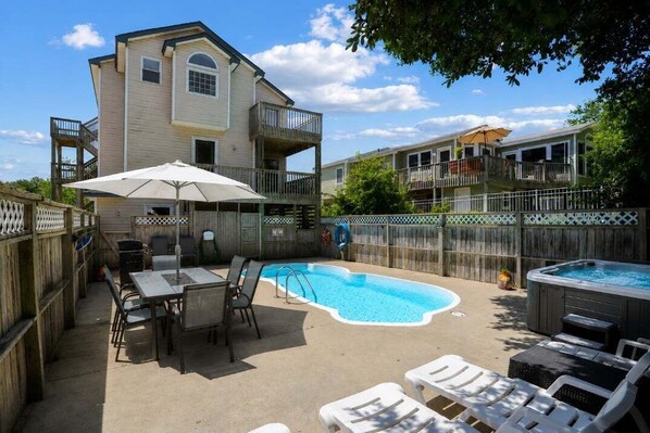 Un jardin avec une piscine, un jacuzzi et du mobilier d’extérieur.