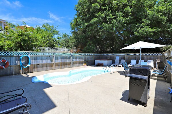 A backyard with a swimming pool, a barbecue grill, and outdoor furniture.