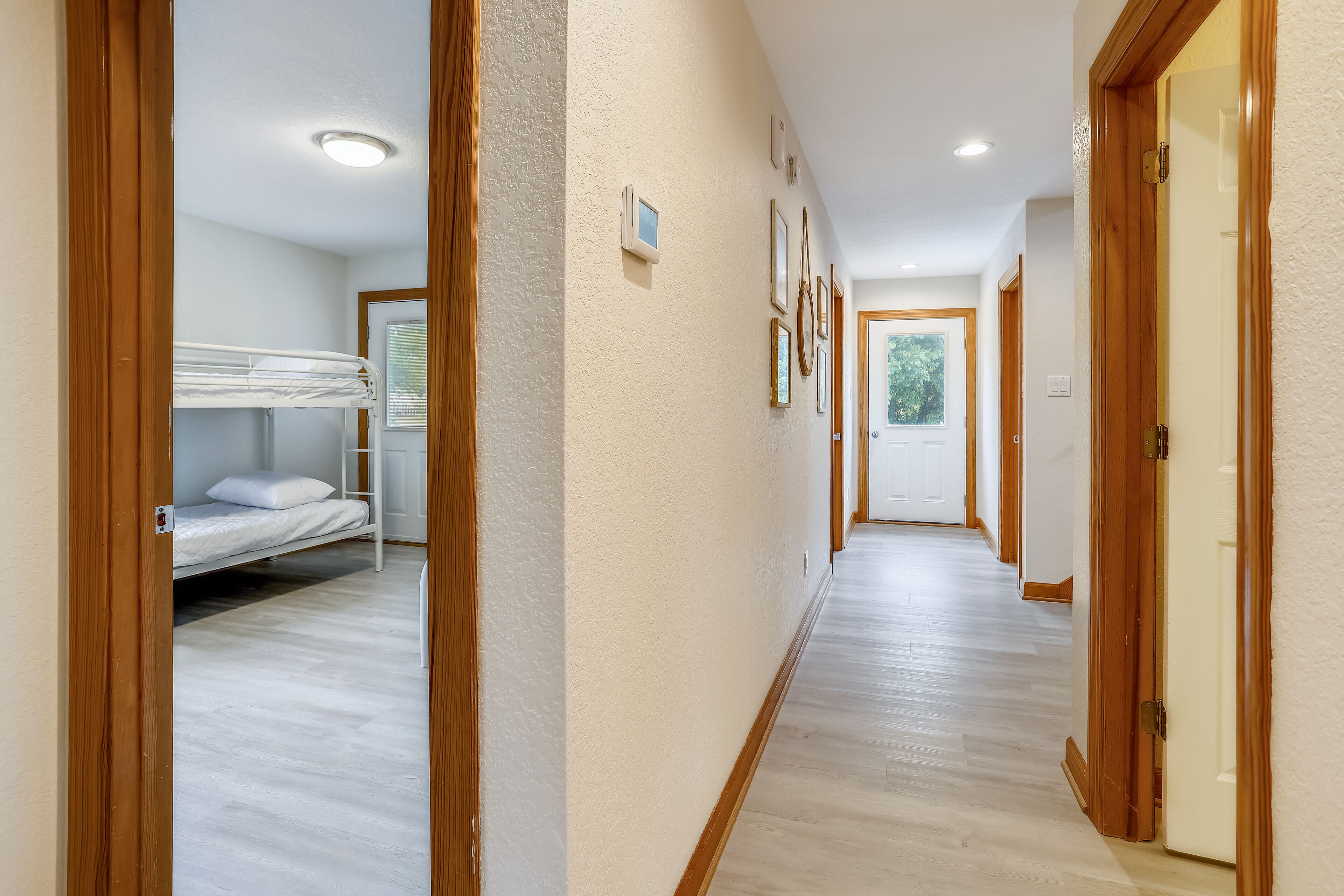 A hallway with a bunk bed in one room and a door leading to another room.
