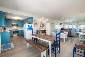 A modern kitchen with blue cabinets, a wooden dining table, and a chandelier. - McInnes 762 5 bedroom ocean front home on the South End of Pawleys! (Pawleys)