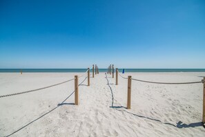 A sandy beach with wooden posts and ropes forming a pathway leading to the water.