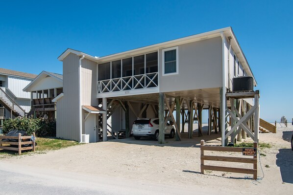 A two-story building with a covered parking area and a balcony. - McInnes 762 5 bedroom ocean front home on the South End of Pawleys! (Pawleys)