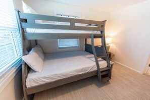 A bunk bed with a window and a bedside table with a lamp.
