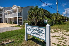 A beachfront property with a sign reading 'Whispering Sands.'