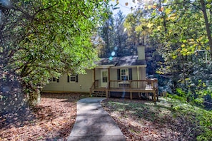 Set amidst a serene wooded area, this charming home features a welcoming front porch and a convenient concrete pathway to the entrance.
