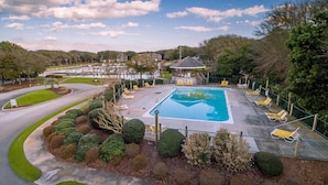 Una piscina con sillones de descanso, rodeada de jardines cuidados y vistas a una zona residencial.